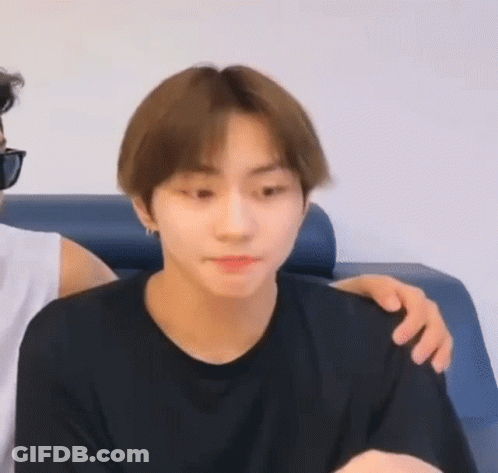 A Man In A Black Shirt Is Sitting On A Couch With His Arm On Another Man 'S Shoulder . GIF