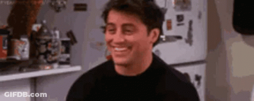 A Man In A Black Shirt Is Smiling In A Kitchen . GIF