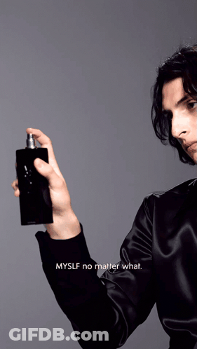 A Man In A Black Shirt Is Spraying A Bottle Of Perfume GIF
