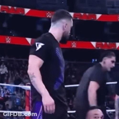 A Man In A Black Shirt Is Standing In A Boxing Ring With Another Man . GIF