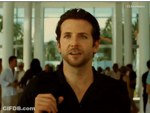 A Man In A Black Shirt Is Standing In A Hallway With A Vibezmaxx Watermark On The Bottom Right GIF