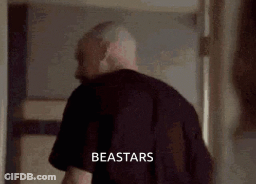 A Man In A Black Shirt Is Standing In A Hallway With The Word Beastars Written On The Bottom Of The Image . GIF