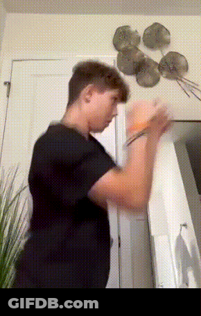 A Man In A Black Shirt Is Standing In A Room GIF