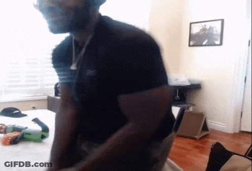 A Man In A Black Shirt Is Standing In A Room With A Picture On The Wall Above Him GIF