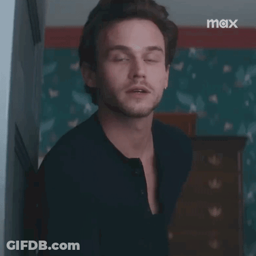 A Man In A Black Shirt Is Standing In A Room With The Words `` Excuse Me '' Written On His Face . GIF