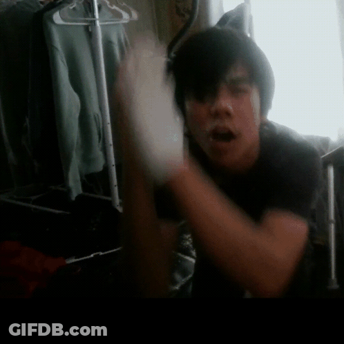 A Man In A Black Shirt Is Standing In Front Of A Closet GIF
