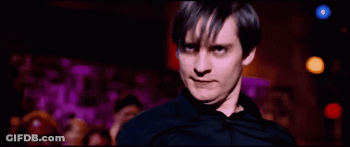 A Man In A Black Shirt Is Standing In Front Of A Crowd Of People GIF