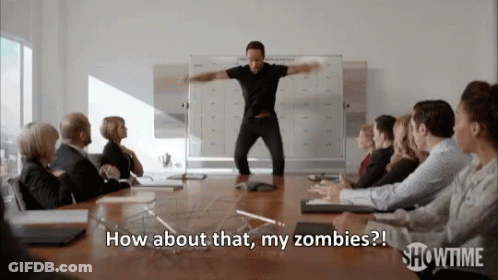 A Man In A Black Shirt Is Standing In Front Of A Group Of People And Says How About That My Zombies GIF