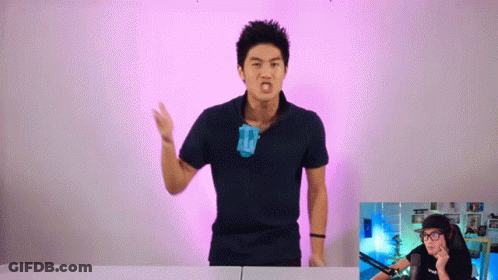 A Man In A Black Shirt Is Standing In Front Of A Pink Background GIF