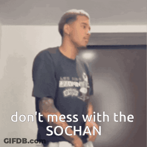 A Man In A Black Shirt Is Standing In Front Of A Sign That Says " Don 'T Mess With The Sochan " GIF