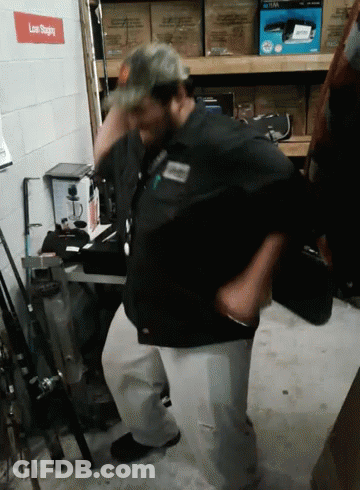 A Man In A Black Shirt Is Standing In Front Of A Sign That Says " Low Sliding " GIF