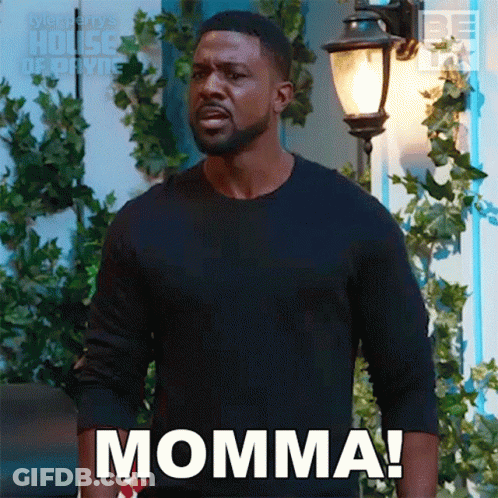 A Man In A Black Shirt Is Standing In Front Of A Street Light And Says Momma . GIF