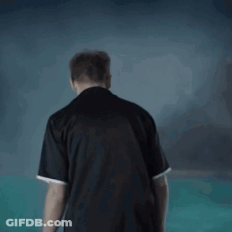 A Man In A Black Shirt Is Standing In Front Of A Swimming Pool . GIF