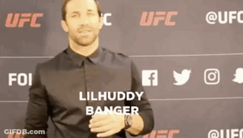 A Man In A Black Shirt Is Standing In Front Of A Wall With Ufc Logos On It GIF