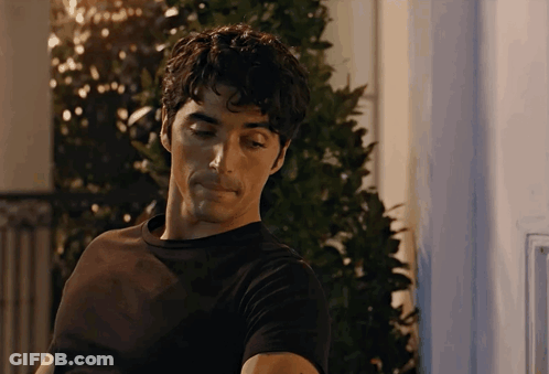 A Man In A Black Shirt Is Standing In Front Of A Window GIF