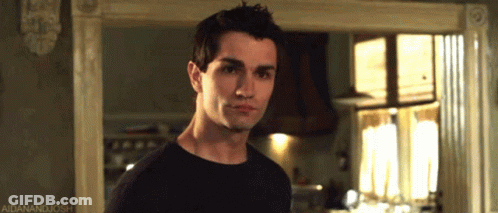 A Man In A Black Shirt Is Standing In Front Of A Window With A Caption That Says Aidanandjosh GIF
