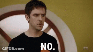 A Man In A Black Shirt Is Standing In Front Of A Yellow Wall And Saying No . GIF