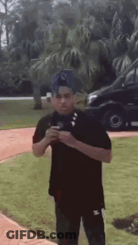 A Man In A Black Shirt Is Standing In The Grass GIF