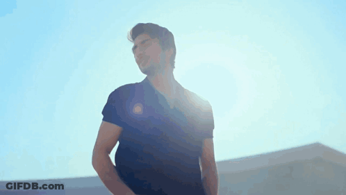 A Man In A Black Shirt Is Standing In The Sunlight GIF