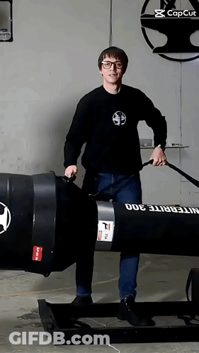 A Man In A Black Shirt Is Standing Next To A Large Black Barrel That Says Integrite 300 On It GIF