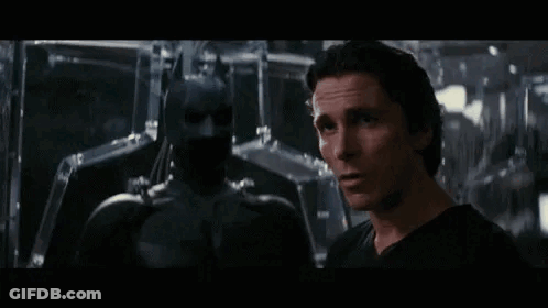 A Man In A Black Shirt Is Standing Next To A Man In A Black Suit . GIF