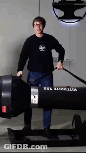 A Man In A Black Shirt Is Standing Next To A Nitebrite 300 GIF