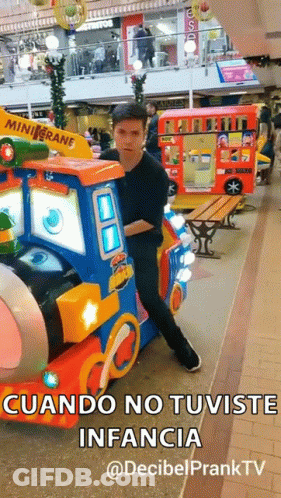 A Man In A Black Shirt Is Standing Next To A Toy Train With The Words " Cuando No Tuviste Infancia " On It GIF