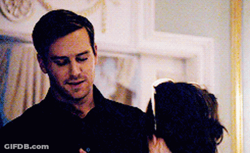 A Man In A Black Shirt Is Standing Next To A Woman In A Dark Room . GIF