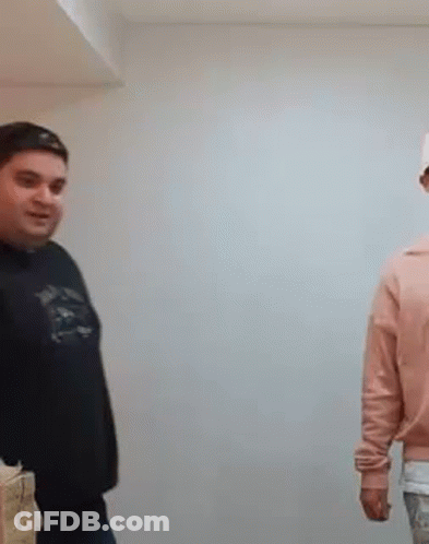 A Man In A Black Shirt Is Standing Next To A Woman In A Pink Sweater . GIF