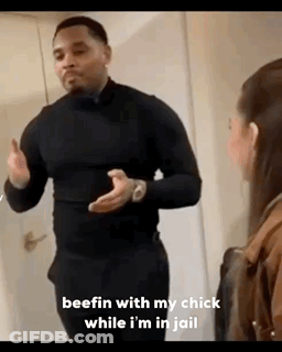 A Man In A Black Shirt Is Standing Next To A Woman In A Room . GIF