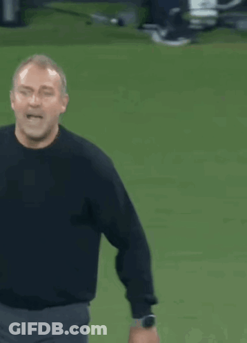 A Man In A Black Shirt Is Standing On A Field With His Arms Outstretched GIF