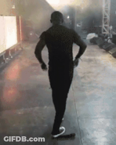 A Man In A Black Shirt Is Standing On A Stage . GIF