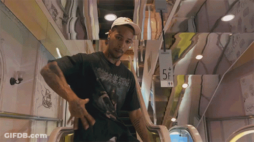 A Man In A Black Shirt Is Standing On An Escalator With A Sign That Says 5F GIF