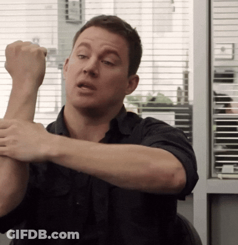 A Man In A Black Shirt Is Stretching His Arms In Front Of A Window GIF