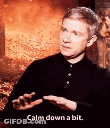 A Man In A Black Shirt Is Talking And Saying `` Calm Down A Bit . '' GIF