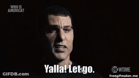 A Man In A Black Shirt Is Talking In A Dark Room And Saying Yalla Let Go . GIF