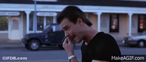 A Man In A Black Shirt Is Talking On A Cell Phone With Makeagif.com At The Bottom GIF