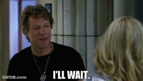 A Man In A Black Shirt Is Talking To A Woman In A Room And Saying `` I 'Ll Wait '' . GIF