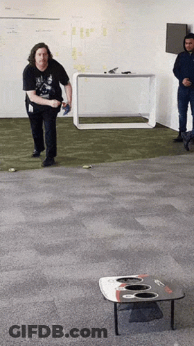 A Man In A Black Shirt Is Throwing A Frisbee In A Room GIF