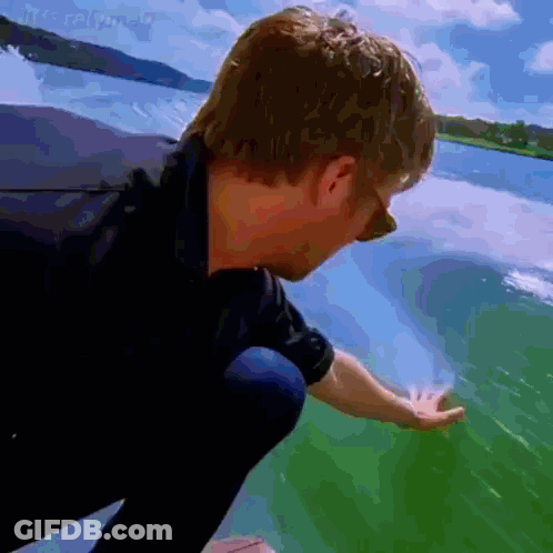 A Man In A Black Shirt Is Touching A Green Surface GIF