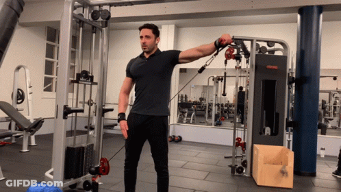 A Man In A Black Shirt Is Using A Machine That Says ' Reebok ' On It GIF