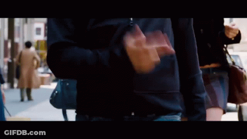 A Man In A Black Shirt Is Walking Down The Street GIF