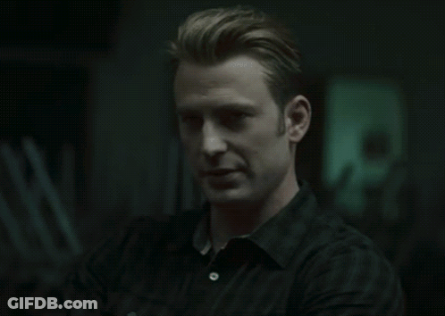 A Man In A Black Shirt Looks At The Camera With His Arms Crossed GIF