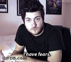 A Man In A Black Shirt Says " I Have Fears " While Sitting On A Bed GIF