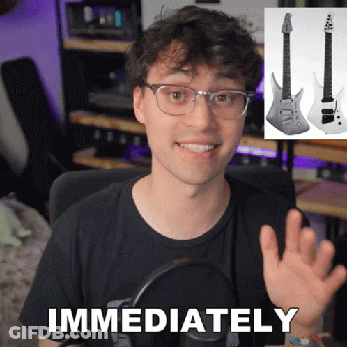 A Man In A Black Shirt Says Immediately In Front Of A Picture Of A Guitar GIF