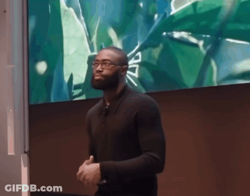 A Man In A Black Shirt Stands In Front Of A Green Screen GIF
