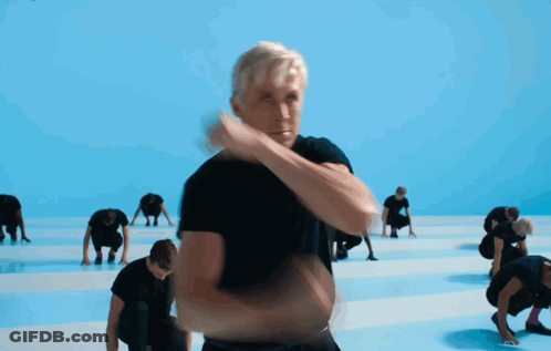 A Man In A Black Shirt Stands In Front Of A Group Of People GIF