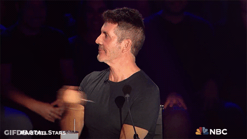A Man In A Black Shirt Stands In Front Of A Microphone With The Nbc Logo In The Corner GIF