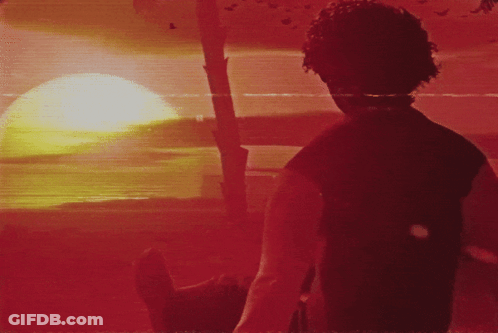 A Man In A Black Shirt Stands In Front Of A Red Sunset GIF
