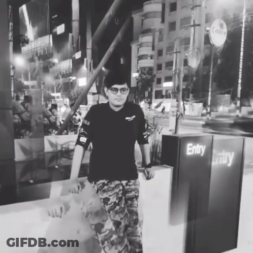 A Man In A Black Shirt Stands In Front Of A Sign That Says Entry GIF
